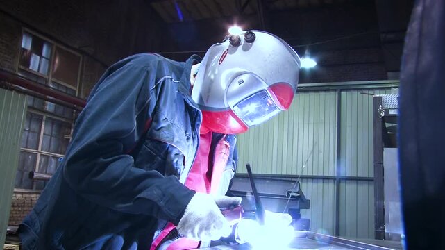 Worker welding in industrial setting