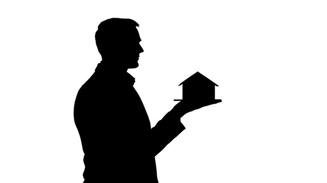 Silhouette of a man holding a miniature house on his palm, symbolizing homeownership and real estate
