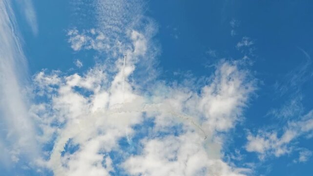 Aerobatic stunt aircrafts performing spectacular aerial maneuvers in the sky, releasing colorful smoke and fireworks. Team formation flight with white smoke trails. 4K video footage