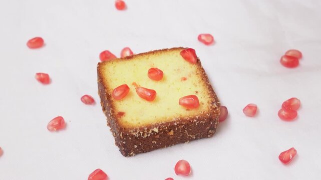 A delicious slice of fruitcake with visible nuts and dried fruit served, isolated on a white background, showcasing a dense and textured interior.