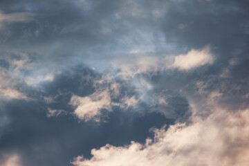 Fototapeta premium Dark storm clouds illuminated by warm golden sunlight during sunset