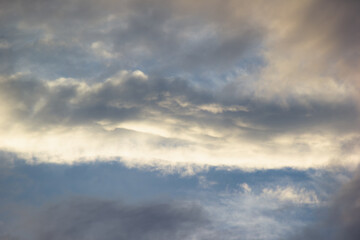 Obraz premium Dramatic dark storm clouds catching golden warm sunlight during sunset