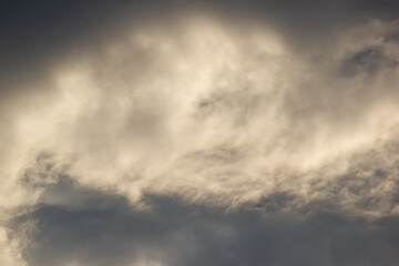 Fototapeta premium Dramatic dark storm sky illuminated by warm sunlight texture background