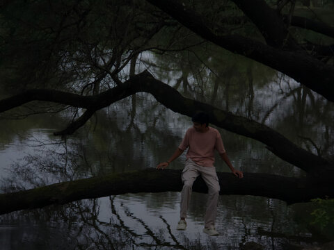 Young Man on Branch Over Reflecting Water