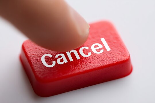 Finger pressing a red cancel button. Close-up of a hand pushing a key to stop or abort an action. Decision and choice concept