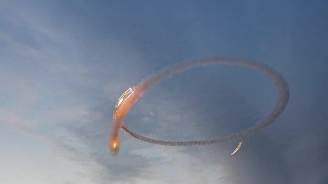 Aerobatic stunt aircrafts performing spectacular aerial maneuvers in the sky, releasing colorful smoke and fireworks. Team formation flight with white smoke trails. 4K video footage