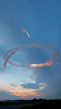 Aerobatic stunt aircrafts performing spectacular aerial maneuvers in the sky, releasing colorful smoke and fireworks. Team formation flight with white smoke trails. 4K vertical video footage