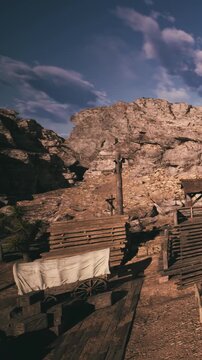 A scene shows wooden structures in a western town setting. A wagon with a white cover is visible, along with a rocky landscape. The sky has clouds with a hint of sunset light.