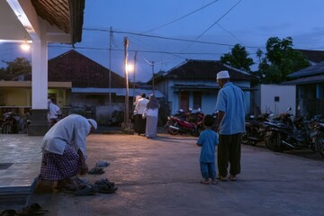 Fototapeta premium muslim men and a young boy gather outside a mosque at dusk for prayer