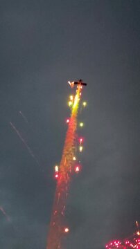 Aerobatic stunt aircrafts performing spectacular aerial maneuvers in the sky, releasing colorful smoke and fireworks. Team formation flight with white smoke trails. 4K vertical video footage