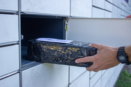 Hand retrieving a wrapped package with shipping label from an automated parcel locker