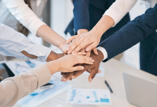 Diverse business team stacking hands together in a symbol of unity and corporate teamwork