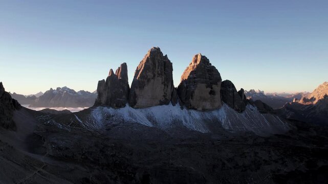 Drone rising above Tre Cime di Lavaredo mountain at sunrise