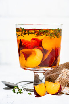 flavored black tea with fresh plums, berries and thyme on white background, vertical closeup