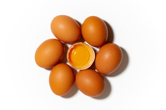 fresh chicken eggs on white background, one broken egg, closeup top view