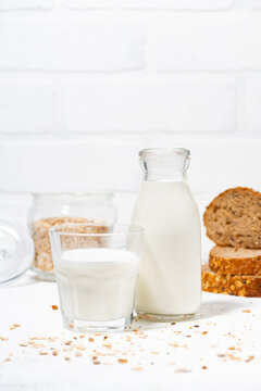 fresh milk and whole grain bread slices on white table