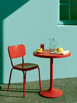 Red cafe table and chair in sunlit minimalist interior