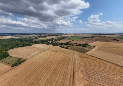 Vue a&eacute;rienne panoramique du village de Saint Supplet, en Meurthe-et-Moselle, entour&eacute; des champs apr&egrave;s la moisson en juillet 2026. Gros  nuages cumulus avec du soleil et un ciel bleu. Paysage rural