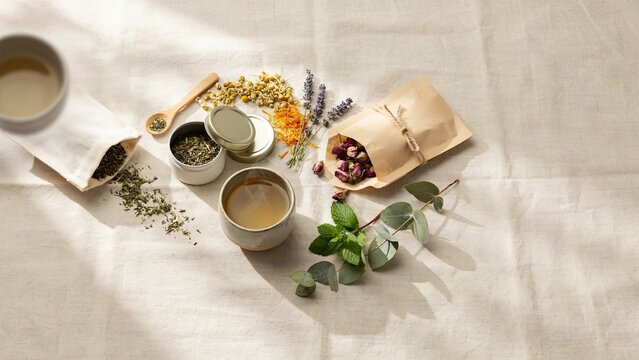 Herbal tea bags and dried flowers are arranged neatly on a linen surface to create a relaxing beverage experience.