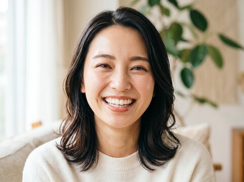 Happy young asian woman with dark hair smiling at the camera in a bright home office setting