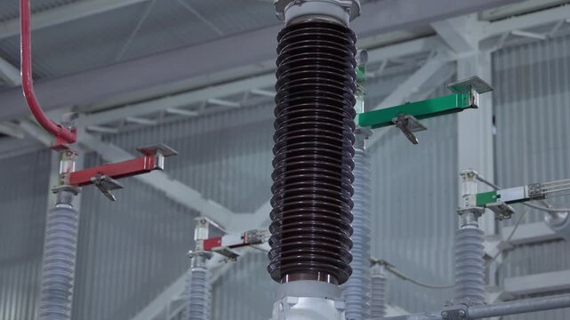 Voltage porcelain insulator assembly mounted between bus connectors inside electrical substation interior, Electricity equipment.