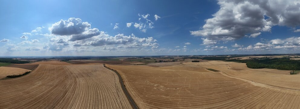 vue a&eacute;rienne panoramique des champs apr&egrave;s la moisson. Paysage rural et agricole en Meurthe-et-Moselle, Lorraine. Ciel bleu avec des gros nuages cumulus en &eacute;t&eacute;. France 2026