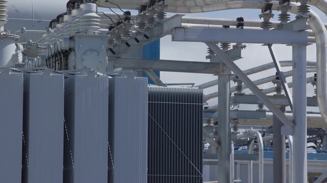 Slow motion reveal of electrical substation transformer units and high voltage equipment in industrial power plant.