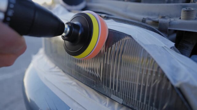 The process of polishing car headlights outdoors. 