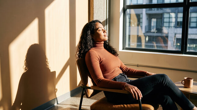 Woman with closed eyes beside sunlit window and coffee