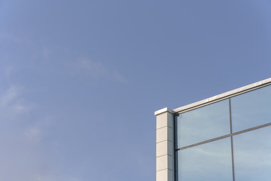A modern glass facade of a commercial office building corner. A minimalist corporate architecture background with vast copy space.