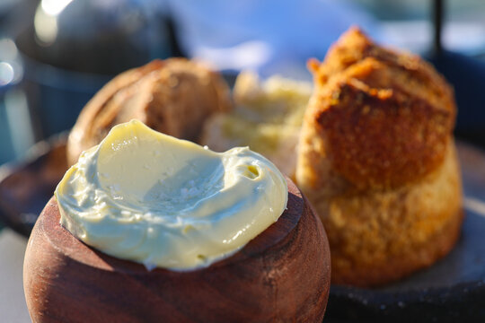 Freshly baked golden bread served with smooth creamy butter in a wooden bowl, highlighting rustic Mediterranean simplicity and warmth in Greece.