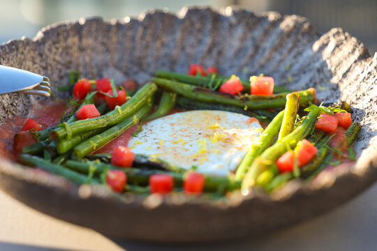 A modern Greek dish of green beans, watermelon cubes, and yogurt sauce arranged artfully in a textured bowl, blending freshness and color in Mediterranean style.
