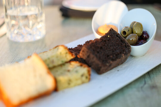 A Mediterranean appetizer of sliced artisan breads, olives, and dip served on a wooden platter in Greece, combining rustic texture and savory flavor.