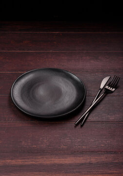 An empty round ceramic plate on a dark, textured brown background. An empty round plate