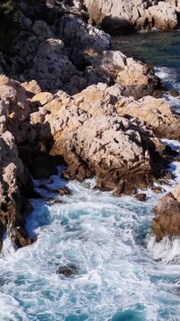 Sea waves splashing with white foam and crashes rocky reef coastline, aerial. Mediterranean sea on South France coast
