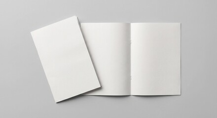 Fototapeta premium Top-down view of open and closed blank white matte bi-fold brochures overlapping on a light grey background with soft diffused shadows.