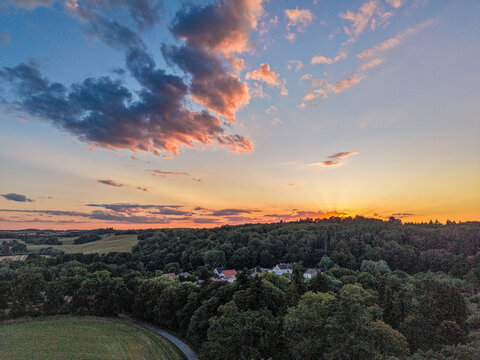 dramatic sunset sky above a forested countryside landscape with colorful evening clouds