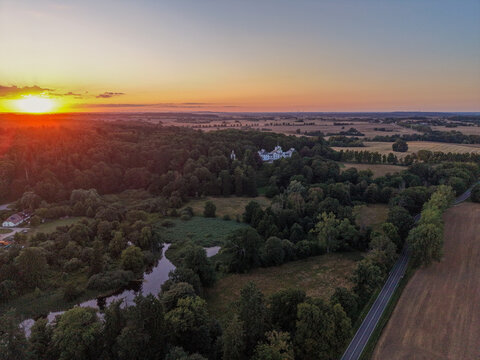 aerial sunset view of a peaceful countryside with forest, ponds and rural farmland