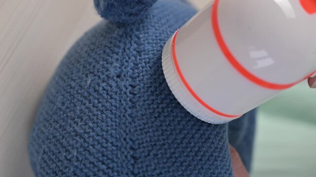 A woman revives the look of her knitted garments with a lint remover.