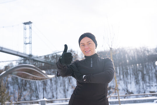 Woman give thumbs up during winter outdoor fitness workout