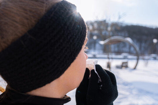 Woman use tissue in winter park on sunny day