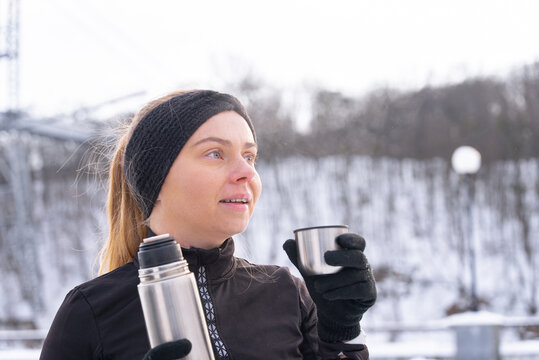 Woman enjoy winter workout outdoors with a hot drink