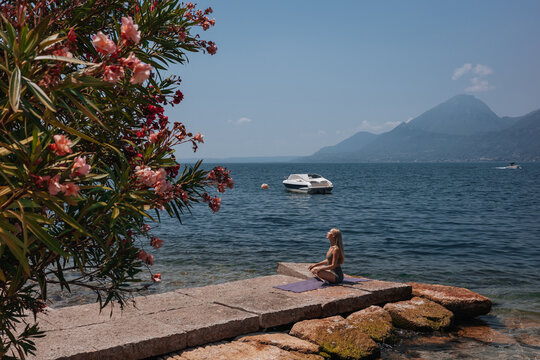 Woman practice fitness yoga by Lake Garda shoreline