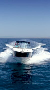 Front view of a sports motorboat cruising with high speed over the blue sea