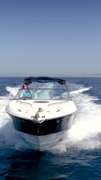 Slow motion front view of a sports motorboat cruising with high speed over the blue sea