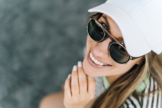 Smiling woman in sunglasses and cap enjoying summer sunshine