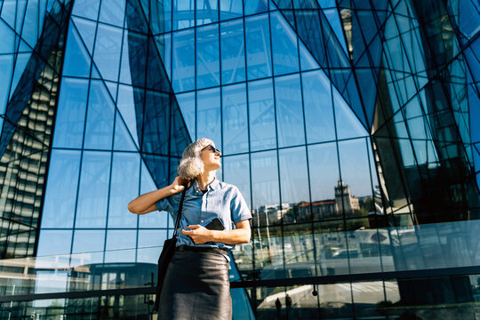 Businesswoman with phone outside modern glass office building
