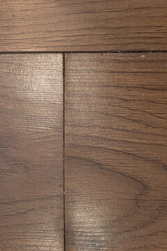 Close-up of swollen laminate flooring, water damage visible along the seam between wood-grain panels