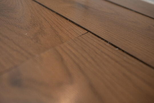 Water-damaged laminate flooring with a swollen seam in a hallway near the bathroom, wide angle with door frame in the background