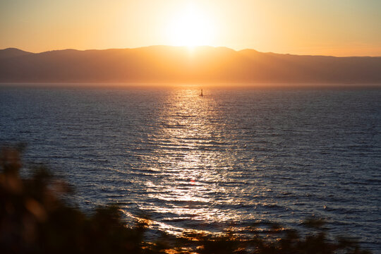 Vibrant sunset over serene sea with distant hills